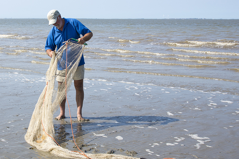 Meneer op het strand met groot vissersnet